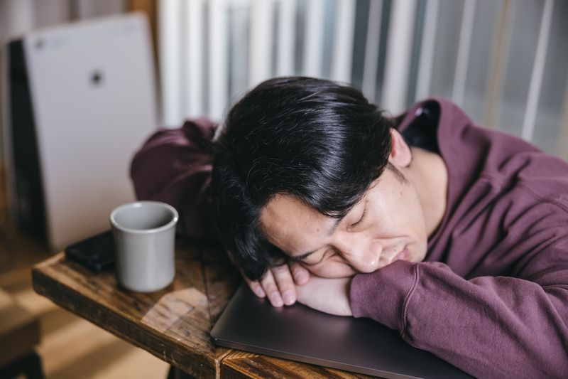 机に伏せて寝る人